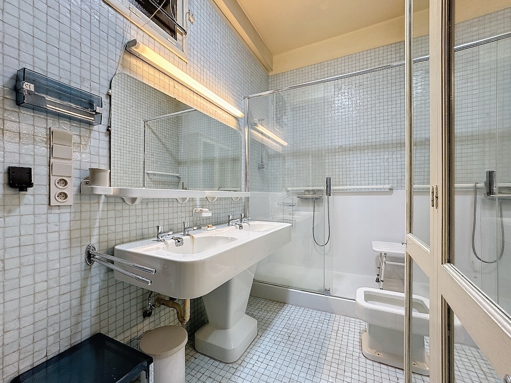Salle de bain moderne minimaliste avec mosaïque bleue, double lavabo, douche en verre et éclairage naturel.
