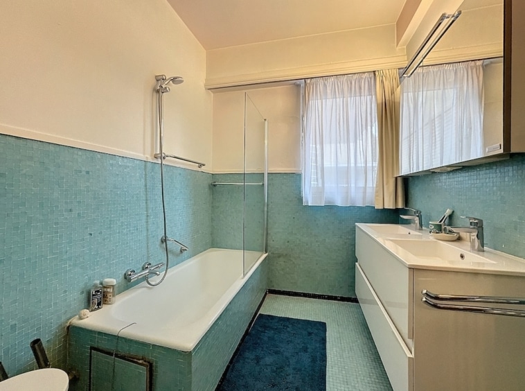 Salle de bain moderne bleu et blanc, lumineuse avec baignoire/douche, double vasques, miroir large.