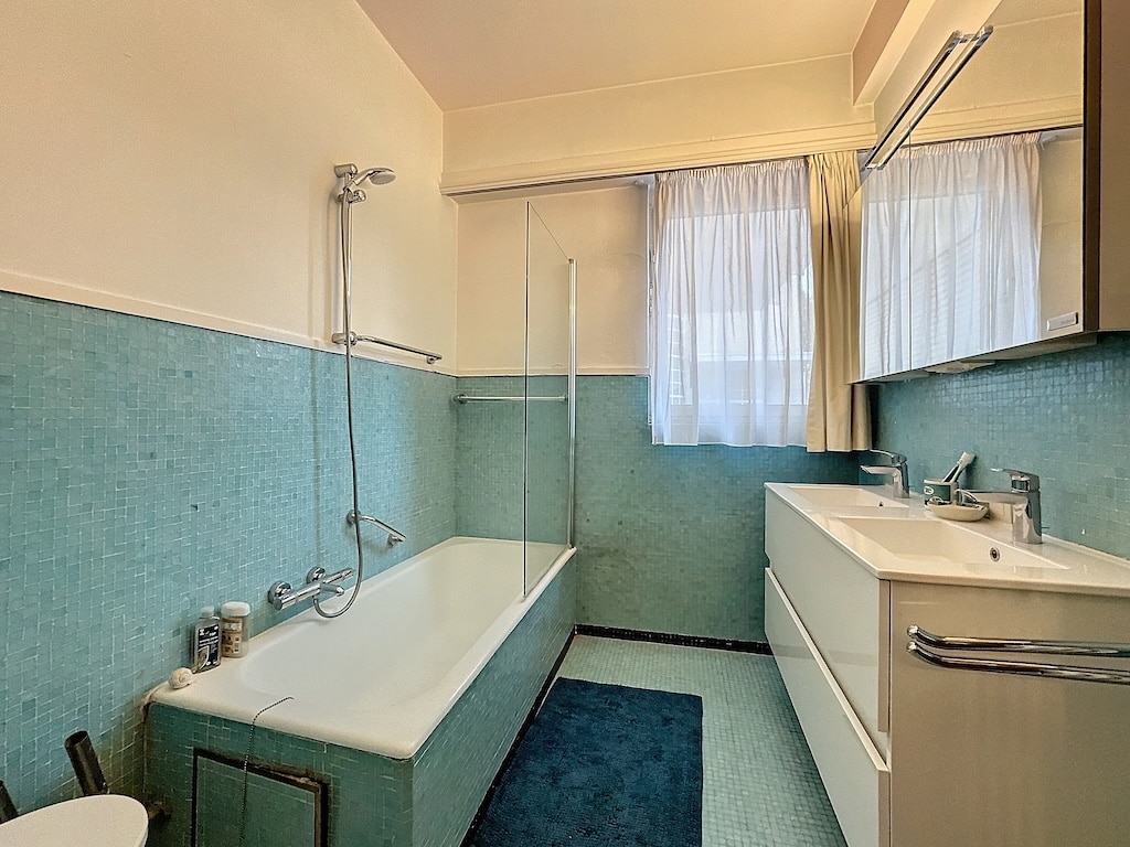 Salle de bain moderne bleu et blanc, lumineuse avec baignoire/douche, double vasques, miroir large.