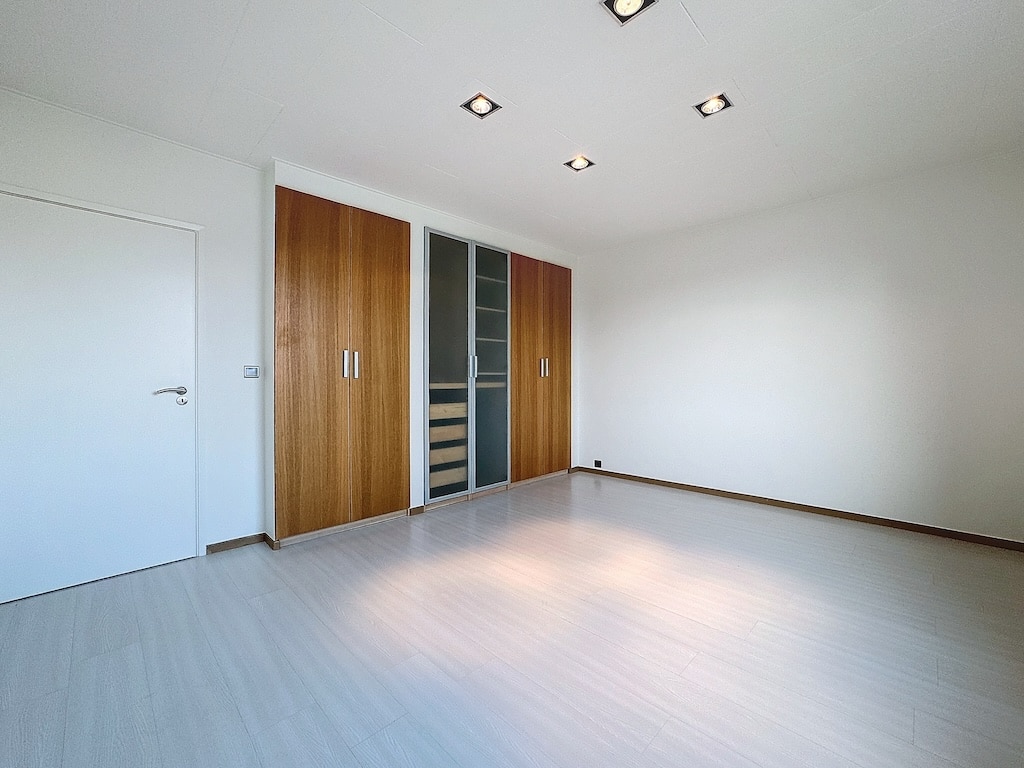 Salle lumineuse minimaliste avec rangements modernes en bois clair et éclairage intégré.