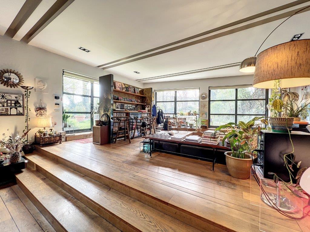 Salon lumineux et cosy, décor rustique moderne avec plantes, œuvres d’art et espace convivial.