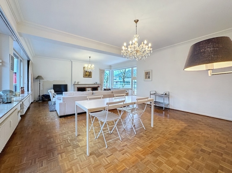 Salon moderne avec parquet chaleureux, grande baie vitrée, espace convivial et décoration élégante.