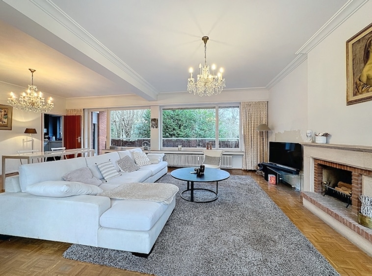 Salon chic et cosy avec vue sur la nature, cheminée, mobilier élégant et lumière naturelle.