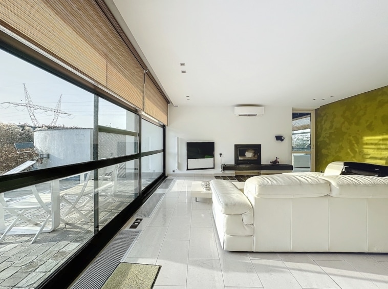 Salon moderne lumineux avec vue panoramique, mur vert vif, mobilier blanc épuré, ambiance chaleureuse.