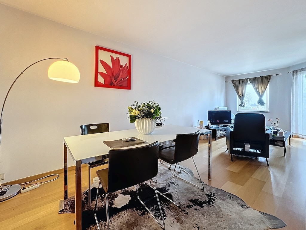 Salon contemporain avec mobilier élégant, art floral coloré, éclairage chaud et ambiance accueillante.