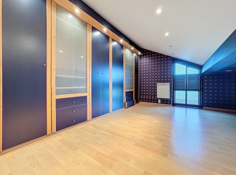 Salon moderne lumineux avec mur bleu, bibliothèque en bois et éclairage LED intégré.