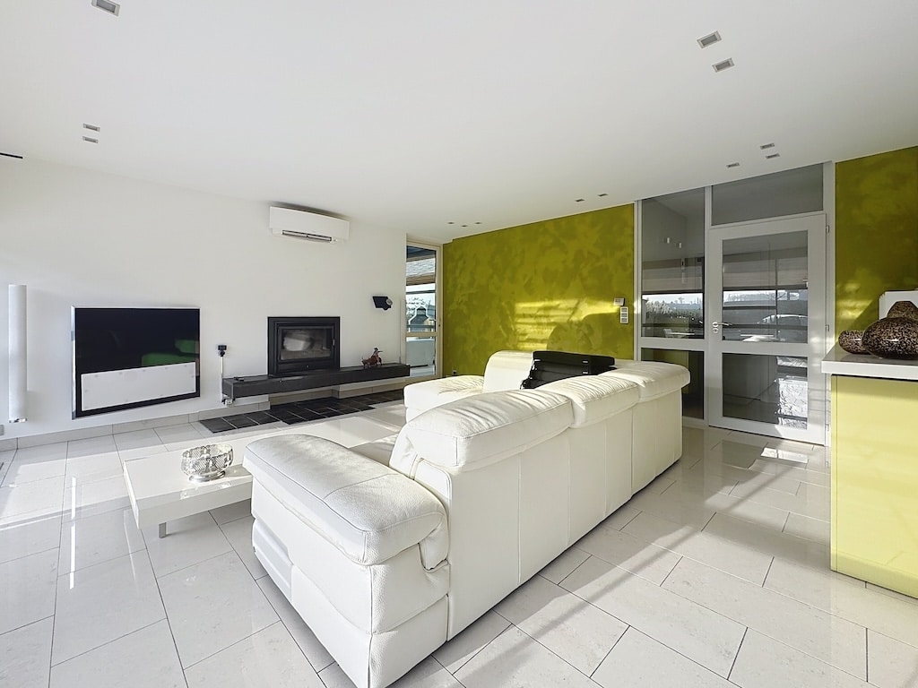 Salon moderne lumineux avec mur vert lime, canapé blanc en cuir et décoration élégante.