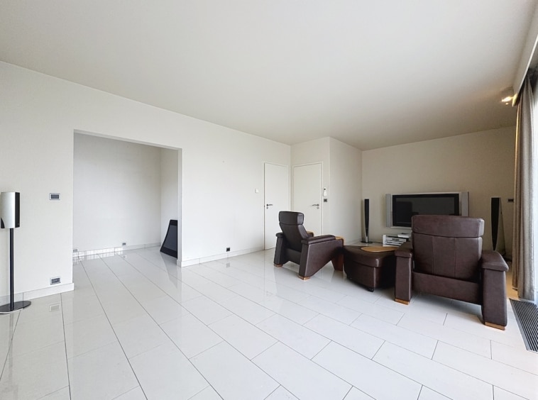 Salon contemporain lumineux avec mobilier minimaliste, grand fenêtres, sol en carrelage blanc brillant.