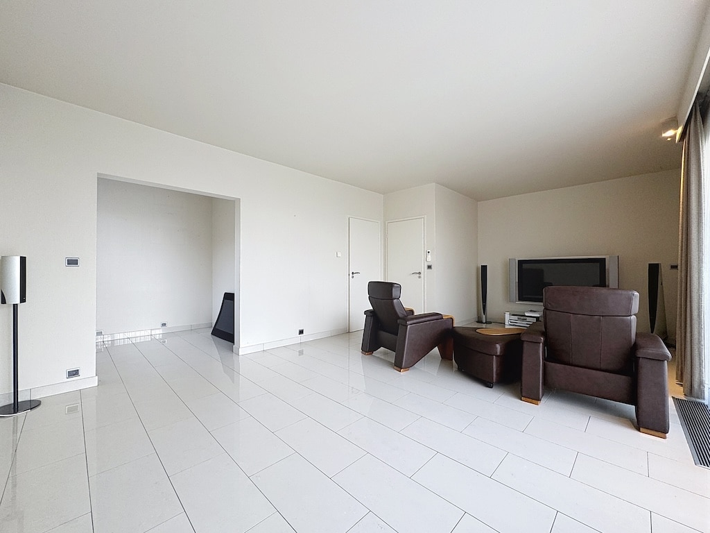 Salon contemporain lumineux avec mobilier minimaliste, grand fenêtres, sol en carrelage blanc brillant.