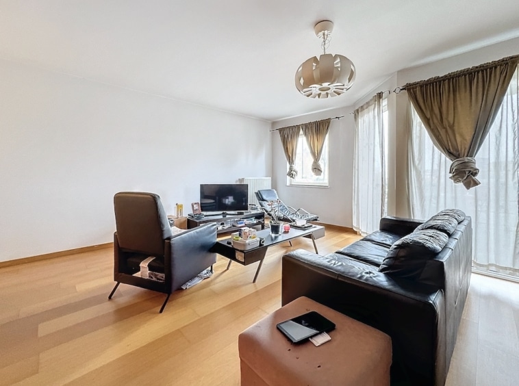 Salon moderne minimaliste avec canapé en cuir noir, mobilier épuré et éclairage naturel.