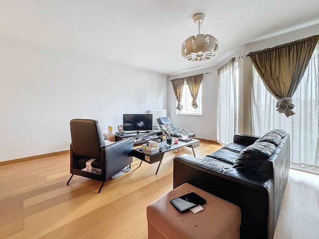 Salon moderne minimaliste avec canapé en cuir noir, mobilier épuré et éclairage naturel.