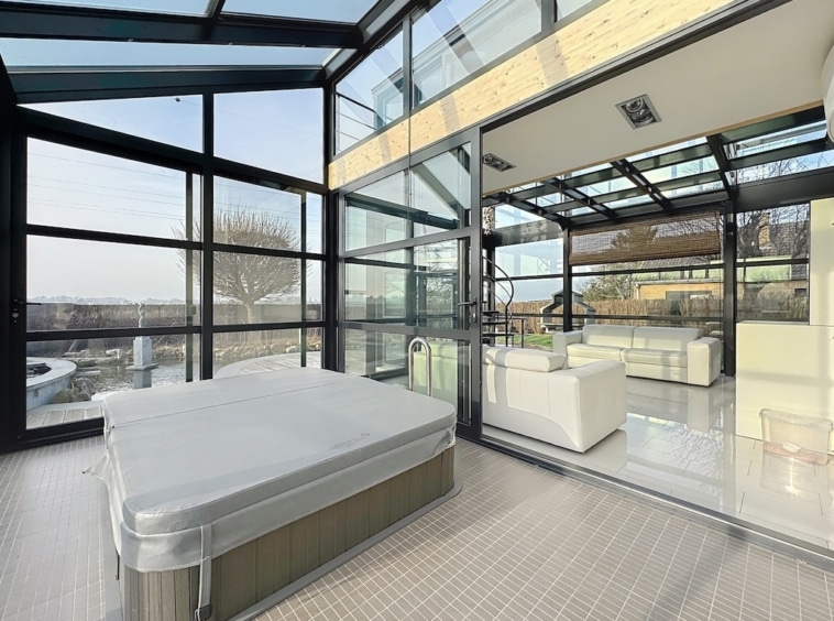 Salon moderne avec vue panoramique, jacuzzi couvert, mobilier élégant, pour détente et luxe naturel.