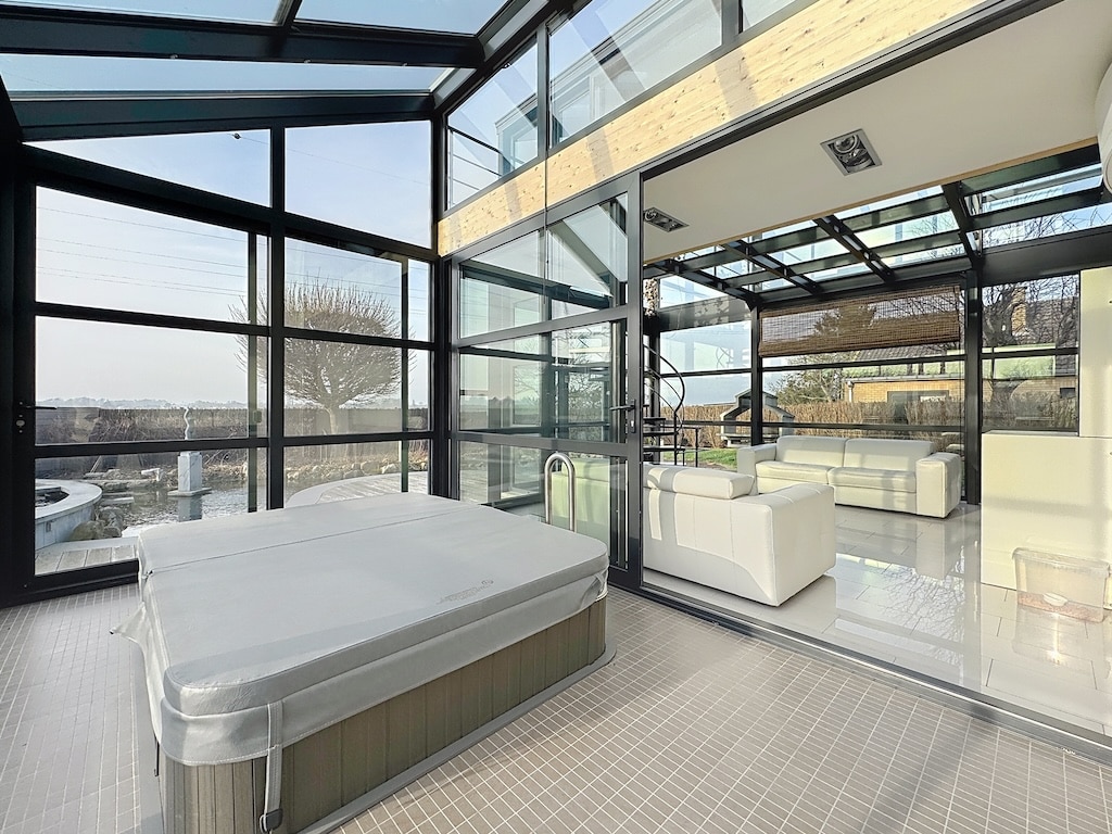 Salon moderne avec vue panoramique, jacuzzi couvert, mobilier élégant, pour détente et luxe naturel.