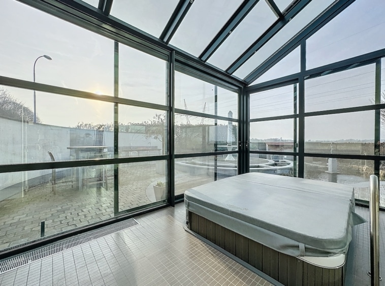 Spa moderne avec jacuzzi et vue panoramique, lumière naturelle, design épuré, espace détente et bien-être.