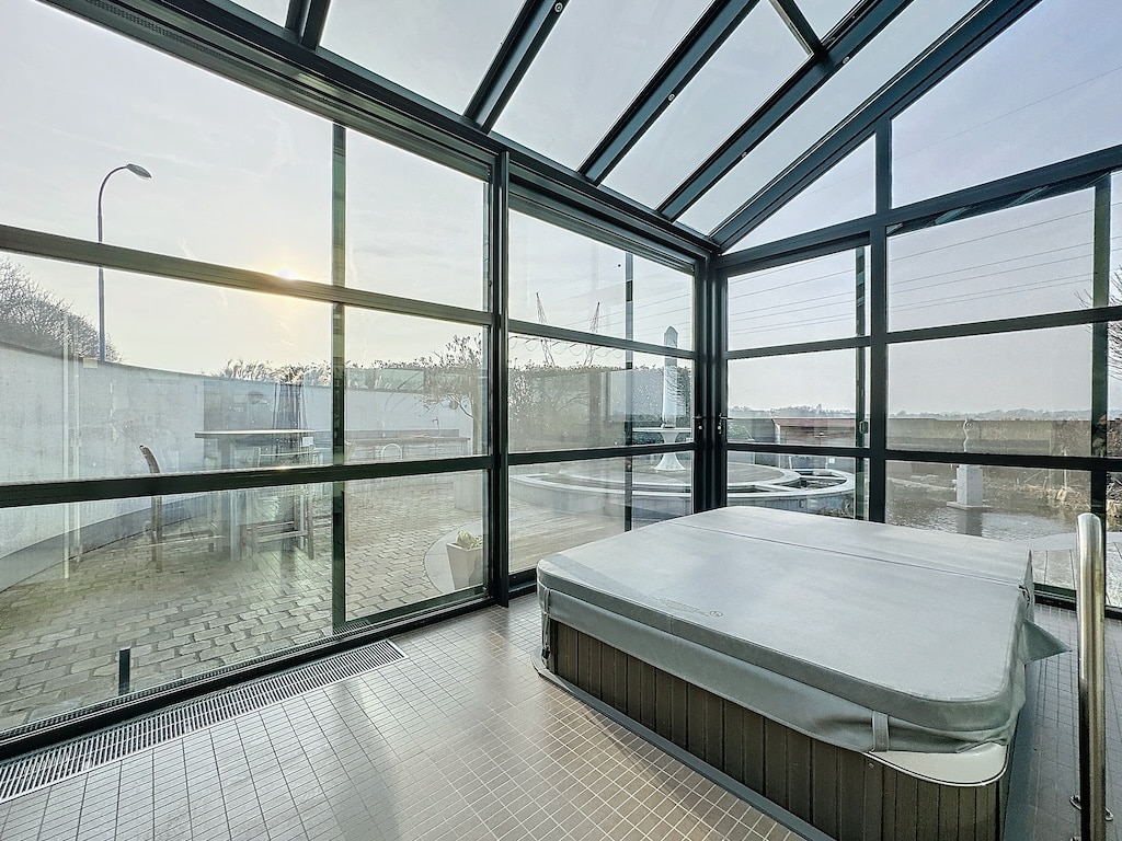 Spa moderne avec jacuzzi et vue panoramique, lumière naturelle, design épuré, espace détente et bien-être.