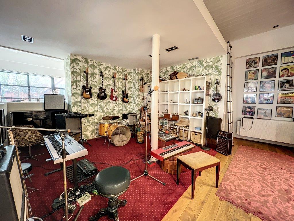 Studio de musique créatif avec guitares, batterie, clavier vintage, ambiance chaleureuse et lumière naturelle.