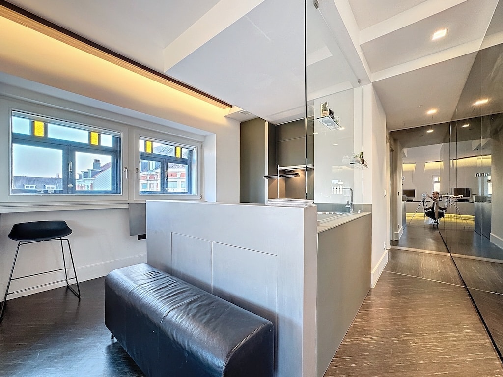 Appartement moderne lumineux avec cuisine ouverte, mobilier minimaliste, grandes fenêtres colorées, ambiance chic.