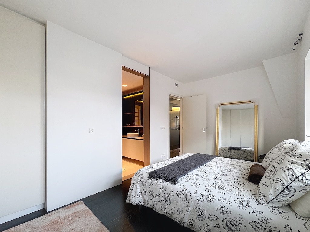 Chambre moderne minimaliste avec lumière naturelle, lit confortable, miroir décoratif et rangement intégré.