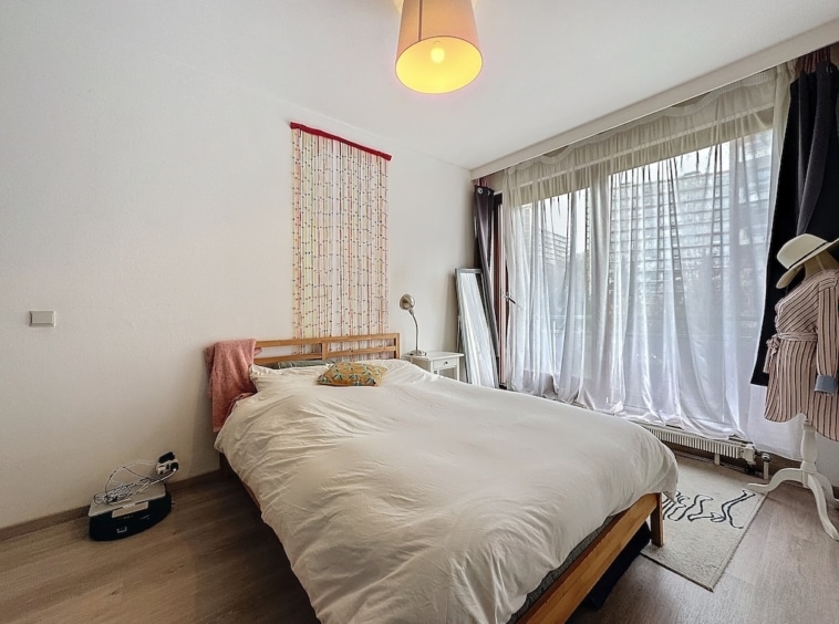 Chambre minimaliste et lumineuse avec lit en bois, rideaux blancs et décor doux naturel.