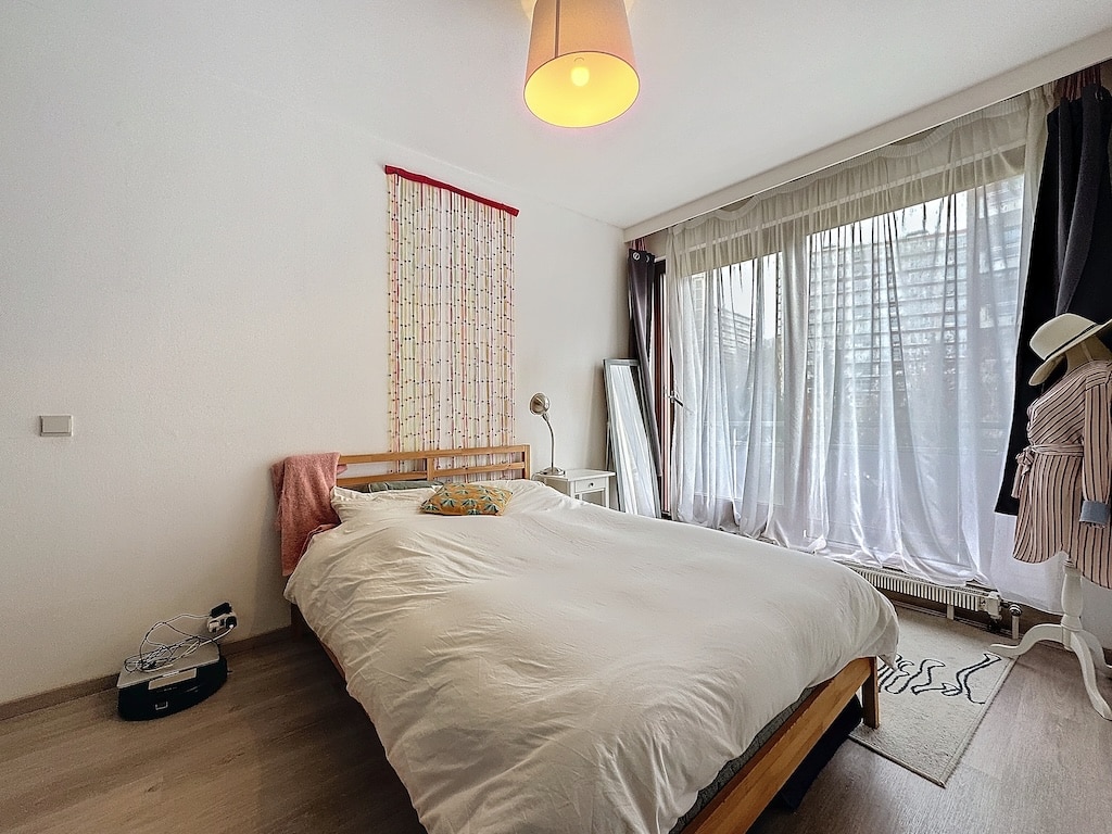 Chambre minimaliste et lumineuse avec lit en bois, rideaux blancs et décor doux naturel.