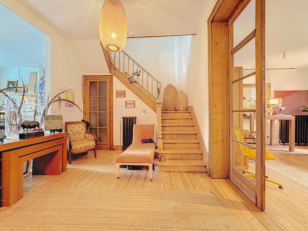 Entrée lumineuse avec mobilier moderne, escalier en bois, décoration colorée et ambiance chaleureuse.