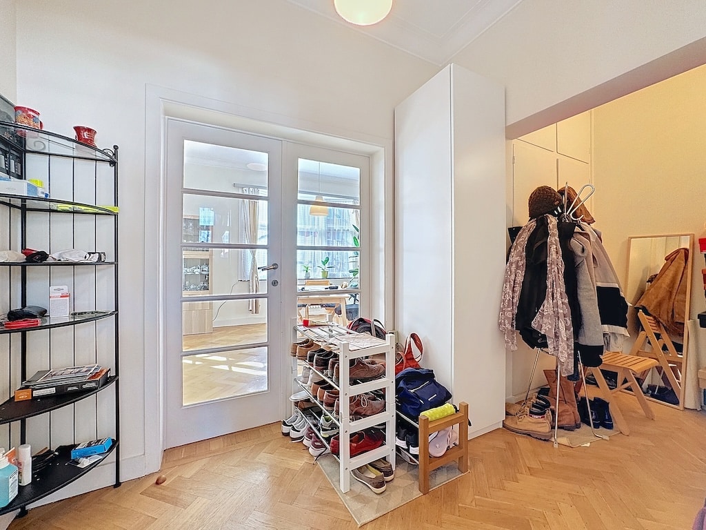 Entrée chaleureuse avec rangements pratiques, portes en verre et sol en bois clair lumineux.
