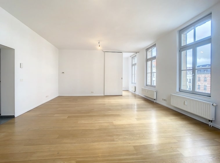 Appartement lumineux au style minimaliste avec murs blancs, parquet clair et grandes fenêtres panoramiques.