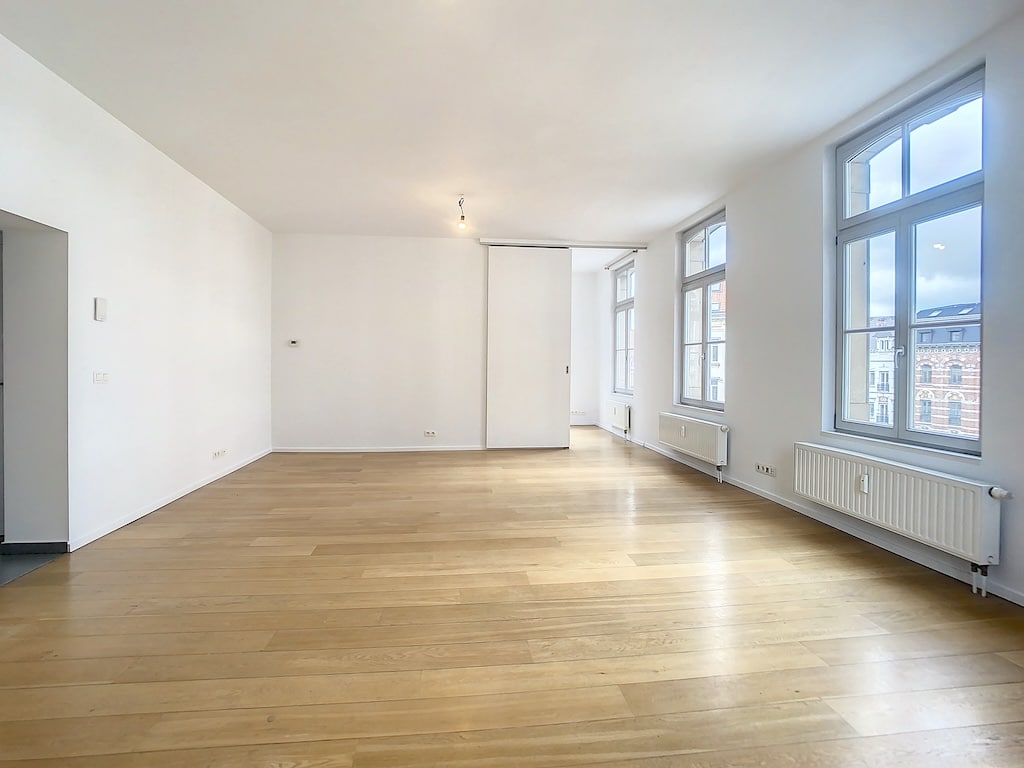 Appartement lumineux au style minimaliste avec murs blancs, parquet clair et grandes fenêtres panoramiques.