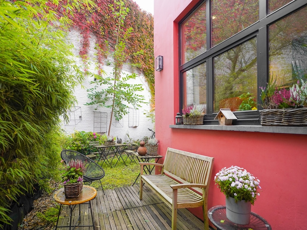 Jardin urbain coloré avec banc en bois, mur fleuri et mobilier de détente lumineux.