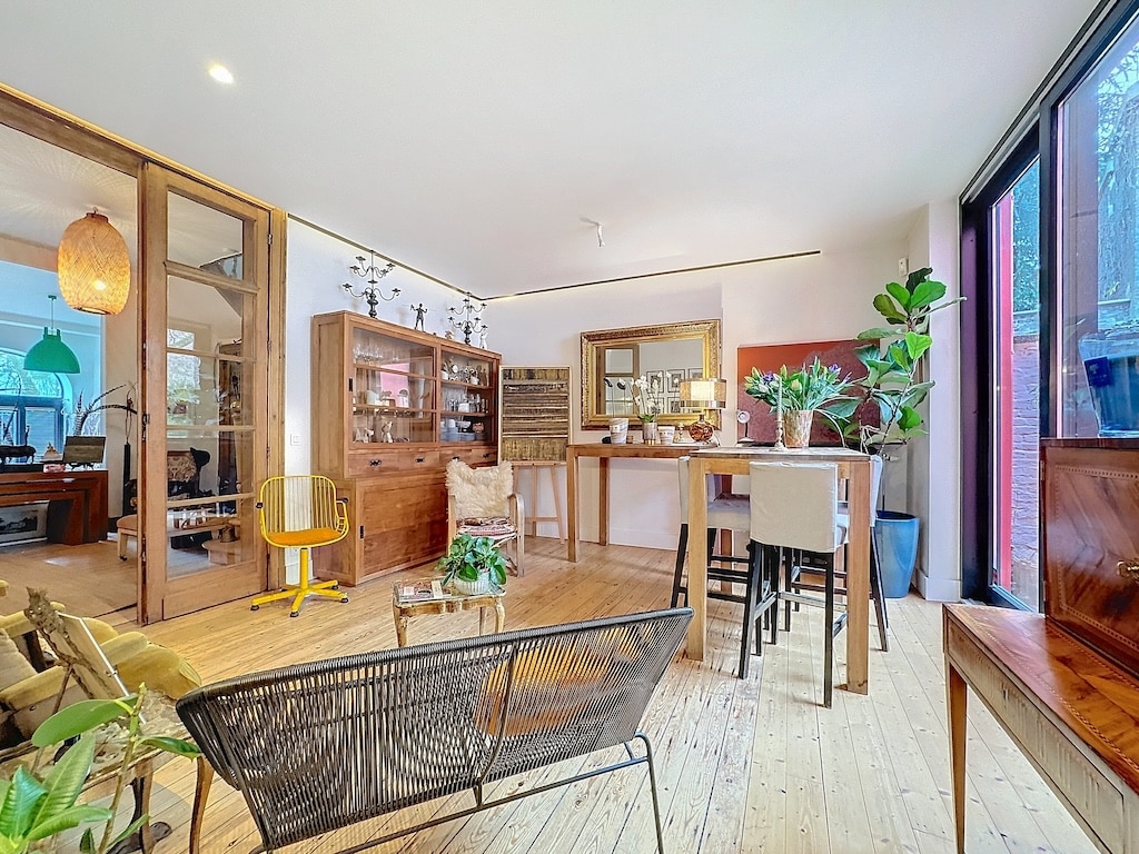 Espace intérieur moderne et chaleureux avec mobilier en bois, plantes vertes et lumière naturelle.