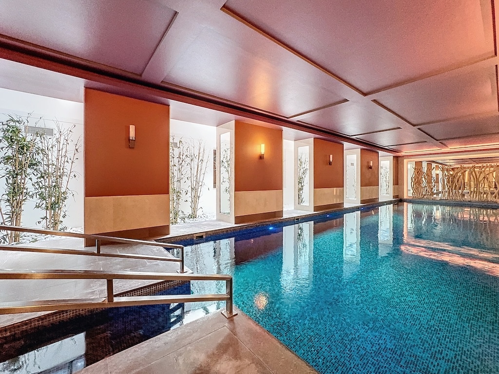 Piscine intérieure moderne et luxueuse avec lumière naturelle, ambiance relaxante et déco élégante.