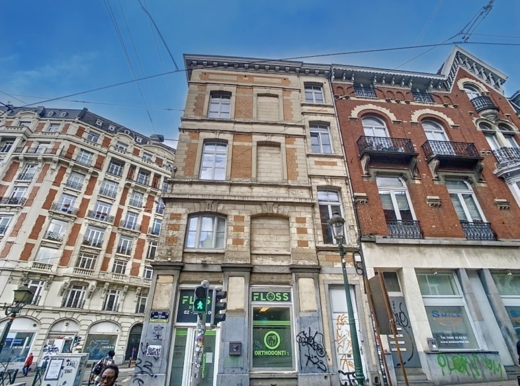 Rue urbaine animée avec bâtiments historiques, modernité et vie quotidienne sous ciel ensoleillé.
