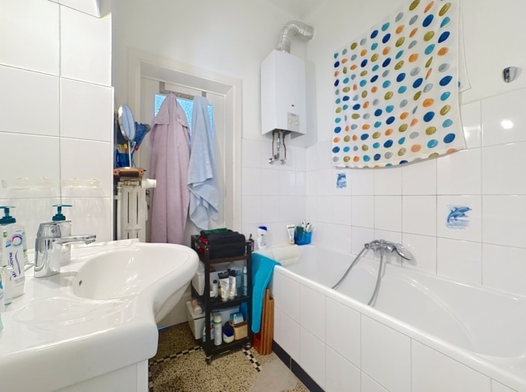 Salle de bain lumineuse compacte avec douche, lavabo moderne et rangement pratique en blanc.