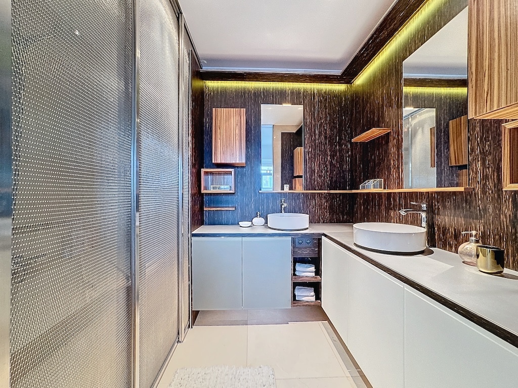 Salle de bain moderne avec bois foncé, douche en verre textured, lavabo rond, ambiance élégante.