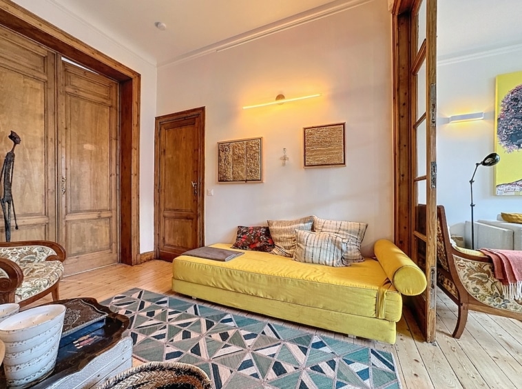 Salon moderne avec canapé jaune, décoration chaleureuse, œuvres earthy et lumière naturelle.