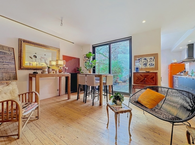 Salon moderne avec cuisine ouverte, terrasse lumineuse, mobilier cosy et décoration artistique élégante.