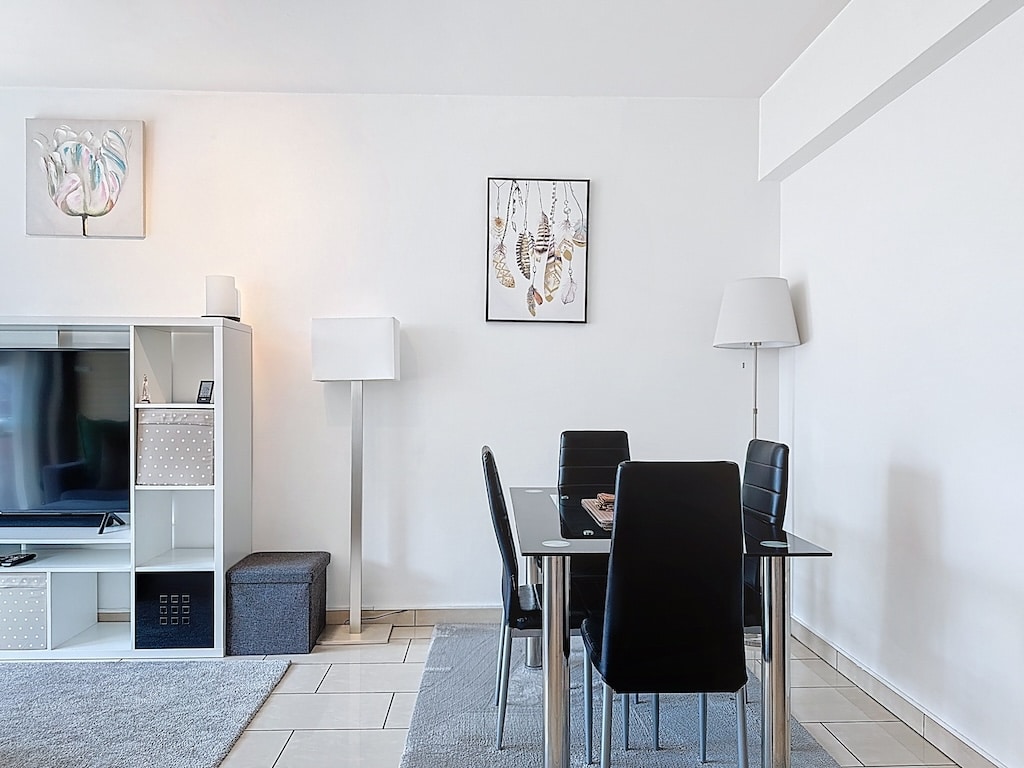 Salon moderne avec table en verre, mobilier noir, éclairage chaleureux, déco minimaliste élégante.