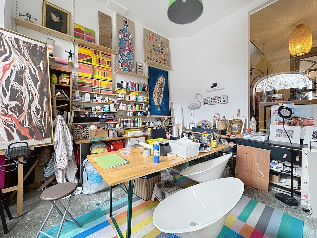 Studio artistique coloré avec baignoire, œuvres vibrantes et environnement créatif inspirant.