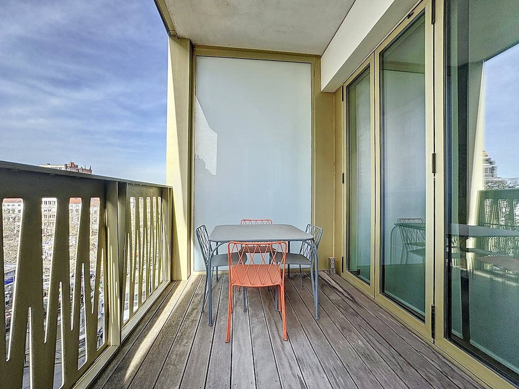 Balcon lumineux avec table colorée, vue apaisante, idéal pour détente et petites réunions.