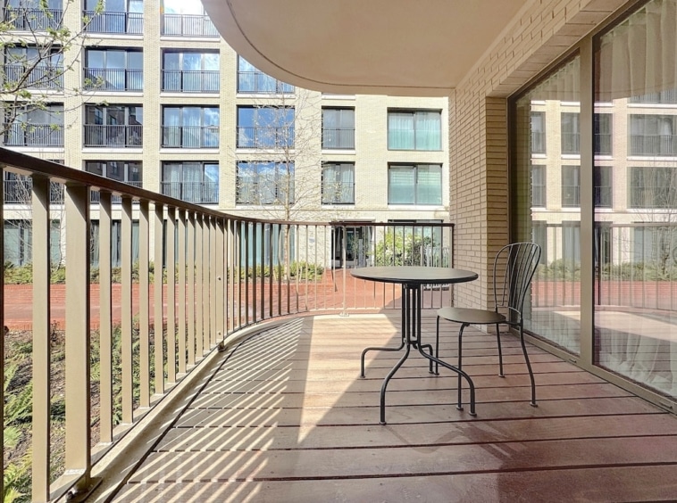 Balcon moderne avec mobilier noir, vue sur jardin verdoyant et lumière naturelle abondante.