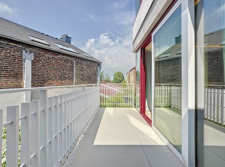 Balcon moderne minimaliste avec vue urbaine, sol clair, railing blanc et porte vitrée.