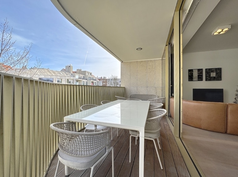 Balcon moderne avec mobilier élégant, vue urbaine et espace détente en bois.