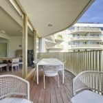 Balcon moderne avec espace repas, lounge cosy, vue urbaine, design minimaliste et luminosité naturelle.
