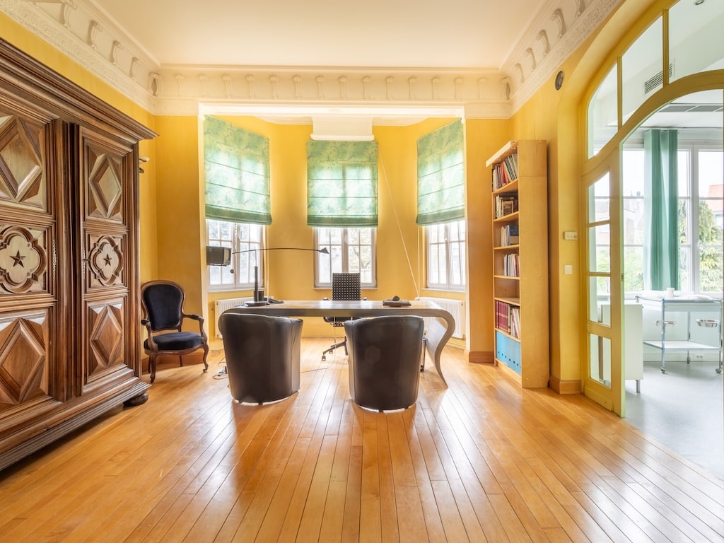 Bureau lumineux avec murs jaunes, mobilier moderne, armoire sculptée et sol en bois chaleureux.