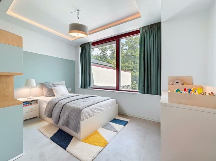 Chambre minimaliste moderne avec espace enfant coloré, lit gris, murs pastel et déco géométrique.