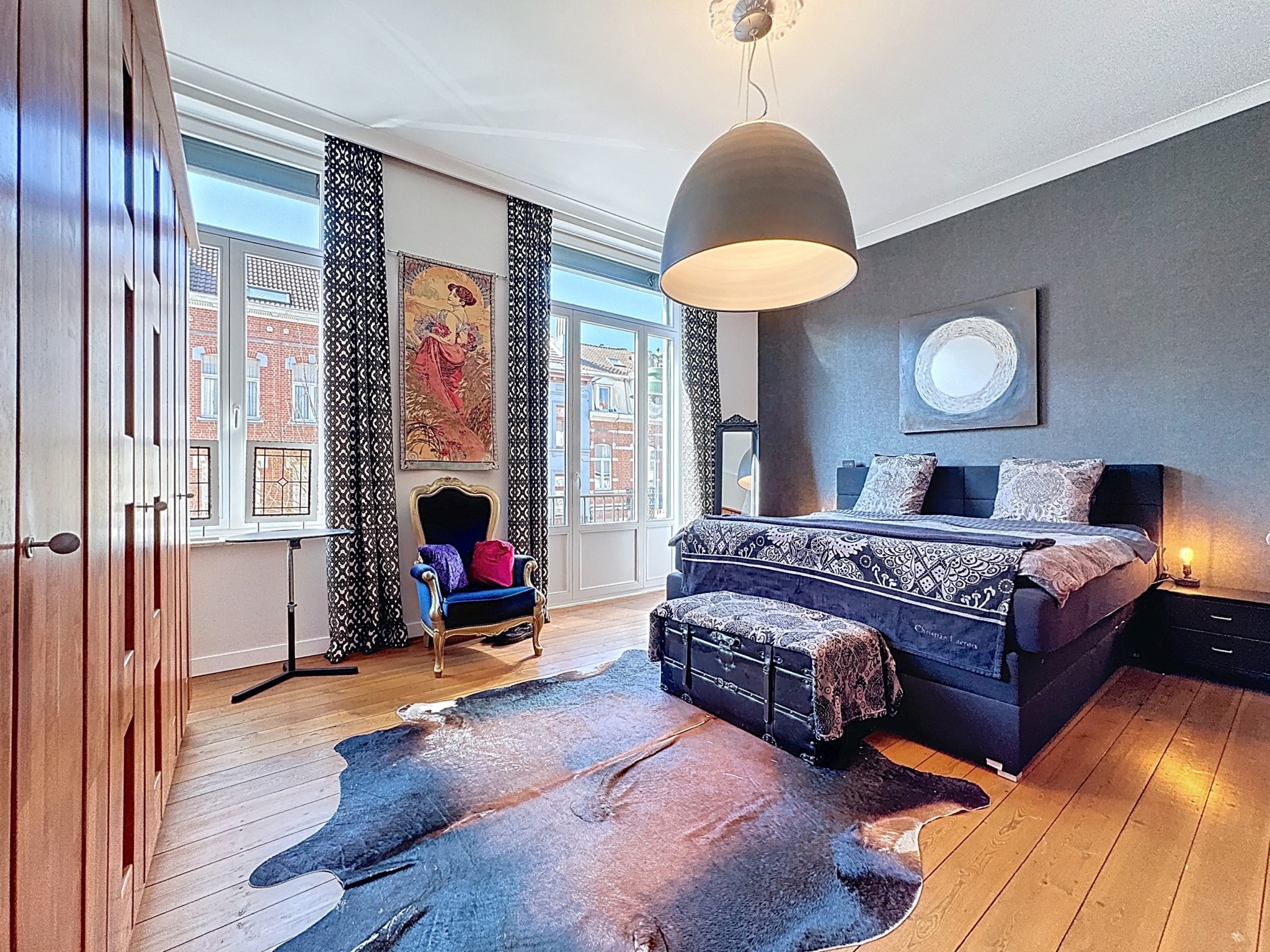 Chambre élégante avec lit raffiné, murs foncés, éclairage moderne, œuvre dart colorée et ambiance chaleureuse.