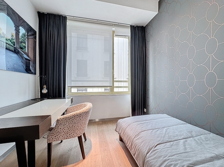 Chambre minimaliste moderne avec lit, bureau, grande fenêtre et décoration géométrique apaisante.