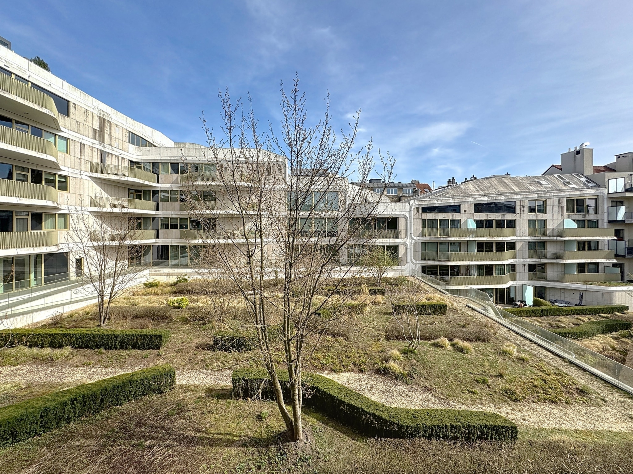 Complexe résidentiel moderne avec architecture minimaliste, espaces verts, et ambiance paisible.