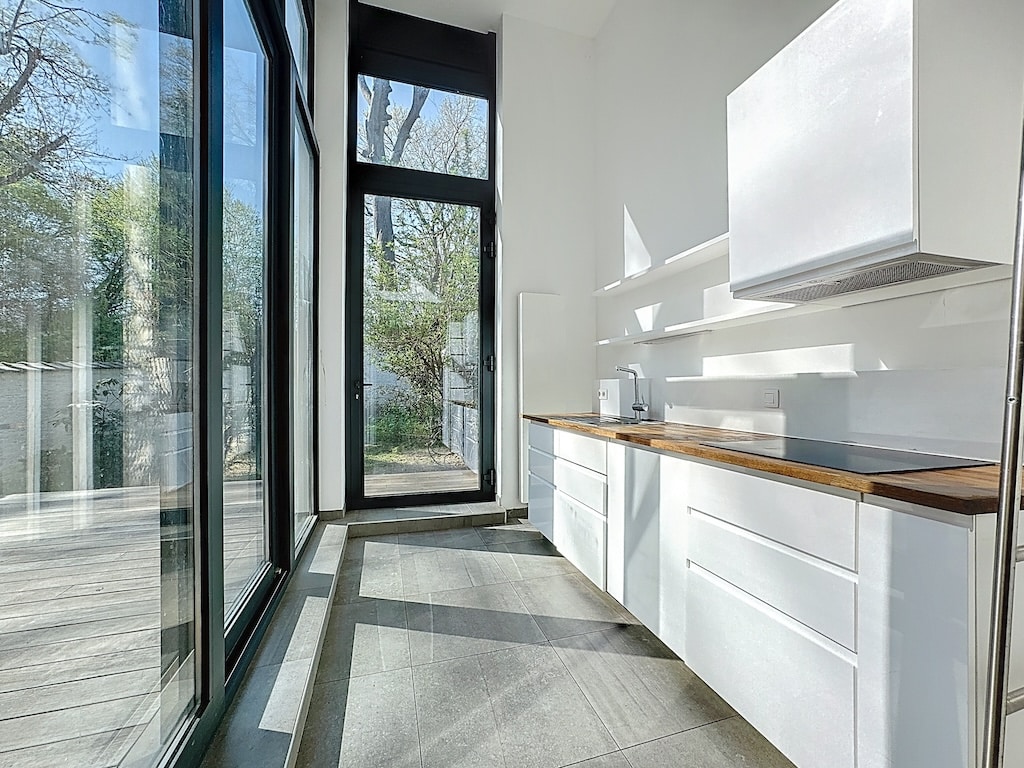 Cuisine moderne lumineuse avec vue sur jardin, bois chaleureux, design épuré, espace convivial et naturel.