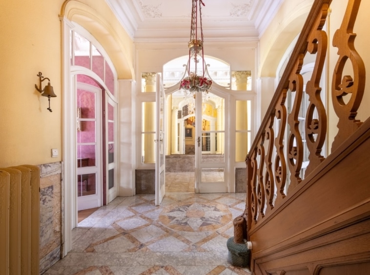 Entrée élégante avec escalier en bois, chandelier chic et murs jaunes lumineux.